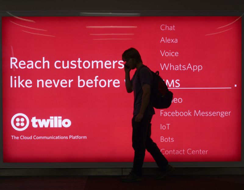 Someone walking in front of an ad. The headline reads "Reach customers like never before with SMS."